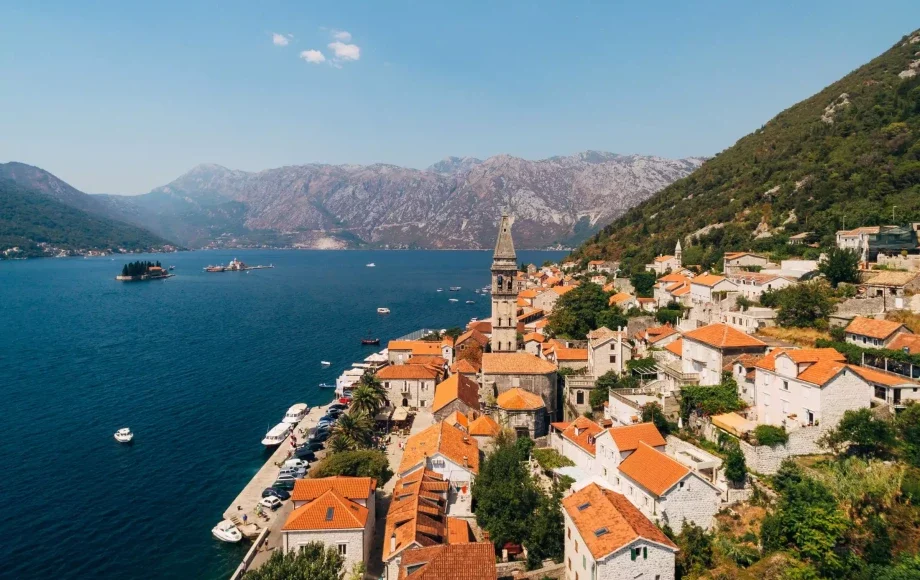 Historic town of Perast along the Bay of Kotor, with its iconic bell tower and two islands in the background.