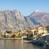 Scenic view of Bay of Kotor, Montenegro, with traditional terracotta-roofed houses and towering mountain backdrop.