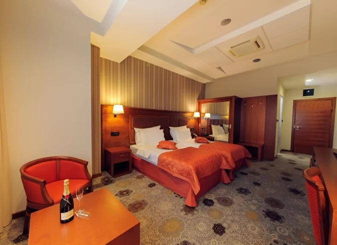 Elegant hotel room in Podgorica at Kings Park Hotel, featuring warm decor and a champagne welcome.