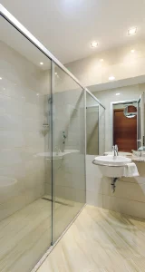 Bathroom at Kings Park Hotel with a glass-enclosed shower, pedestal sink, and bright lighting.