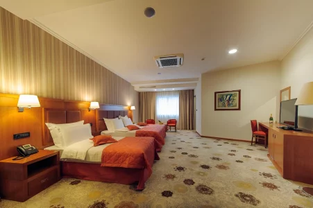 Spacious triple guest room at Kings Park Hotel with multiple beds, elegant decor, and ample lighting, perfect for a family holiday in Montenegro.
